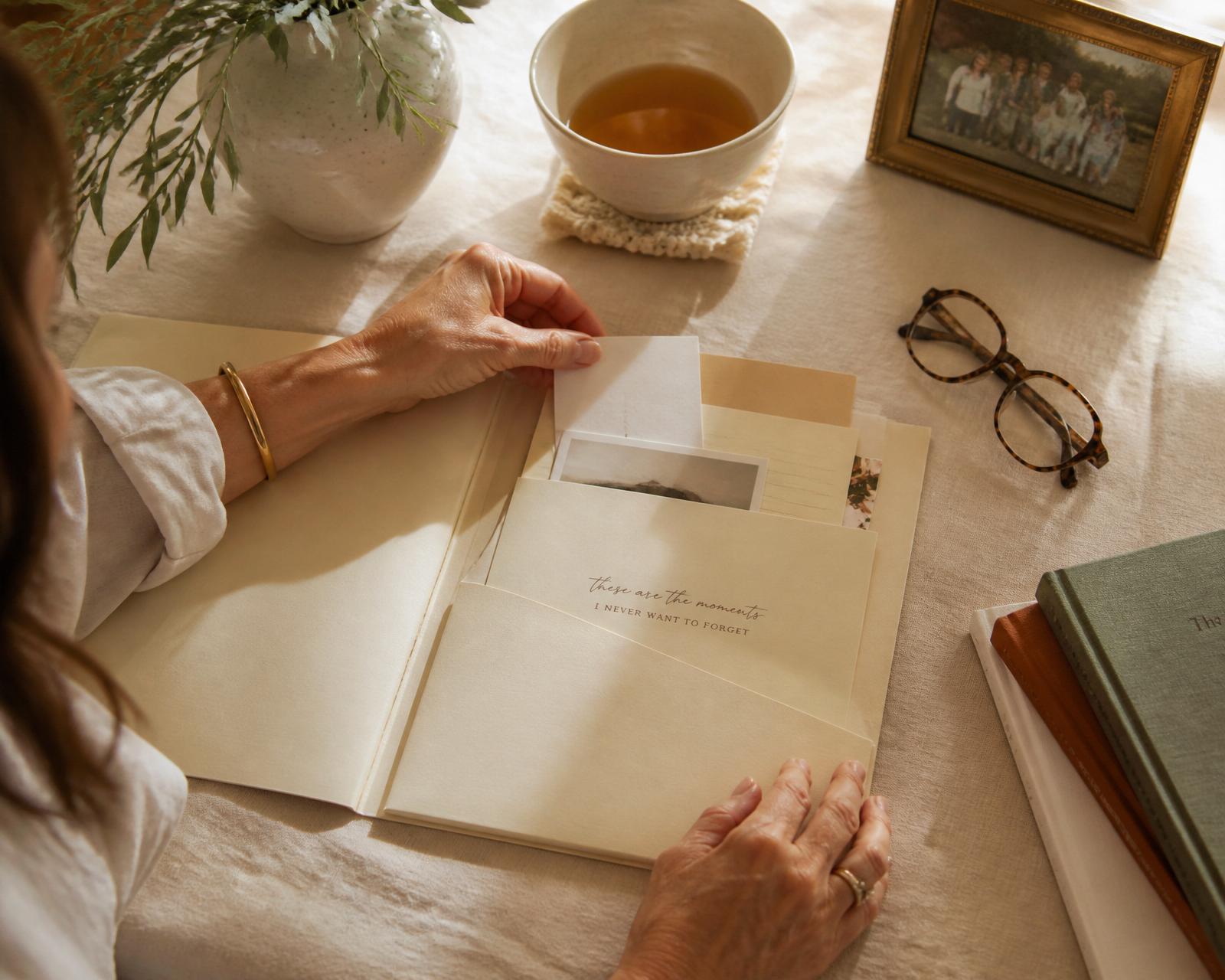 A woman organizing a caregiving folder with tea and family photo nearby